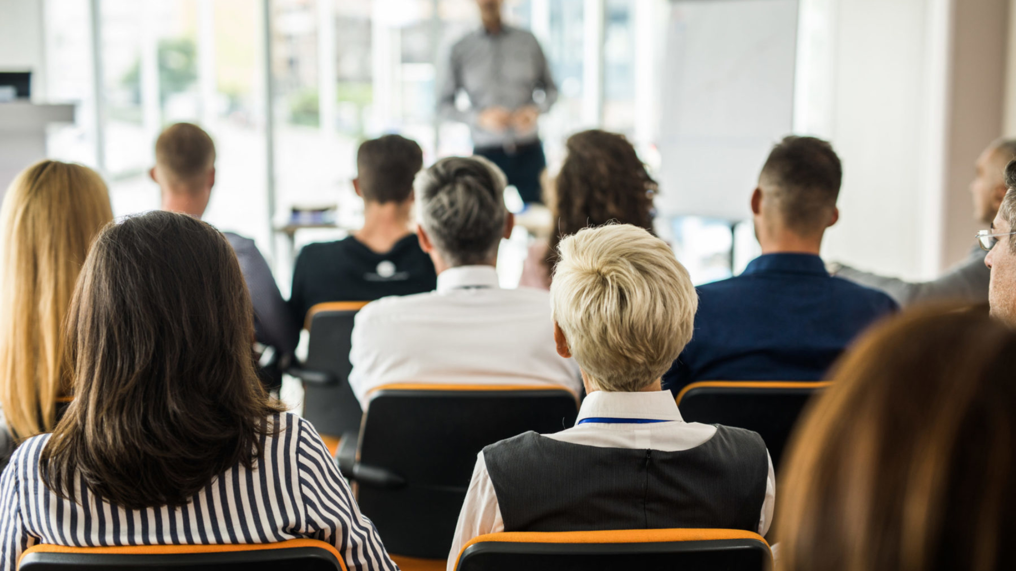 Back view of large group of business people attending a training class in a board room.